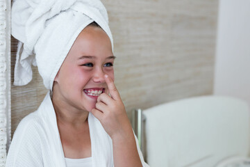 White bathrobe and towel turban resting on bench while beige tile walls gleaming in home bathroom
