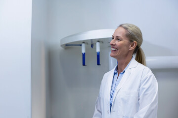 Panoramic dental X-ray machine is hanging on light grey wall with blue handles in dental clinic