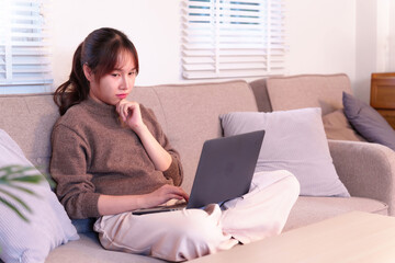 Fototapeta premium Asian woman focused on laptop at home contemplating AI integration into daily life and future technology