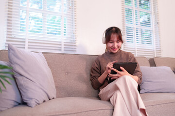 Asian young adult woman deeply immersed in AI powered digital experiences using a tablet and...