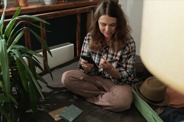 Online payment. Woman books a last minute tour using bank card and smartphone at home 