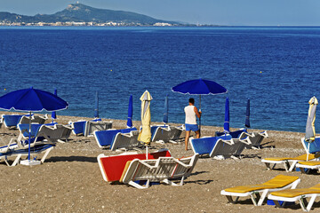 Sunny and peaceful beach on the island of Rhodes, Greece. The sand is golden and dotted with yellow...