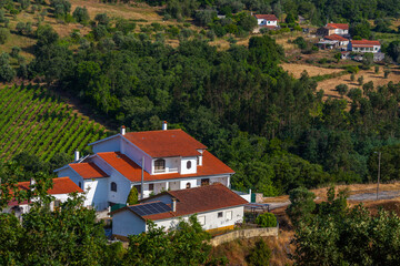 A white house with a red-tiled roof sits amidst lush greenery