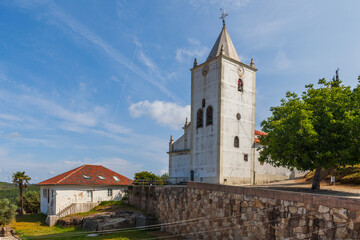 A stone wall with crenellated towers overlooks a white portuguese church