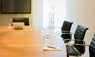 A modern, empty conference room set for business on wooden table, arranged chairs, and neatly...