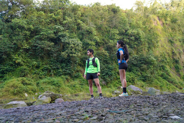 Asian Indonesian couple standing on rocky trail, active outdoor sport and sustainable lifestyles