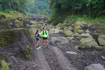 Asian Indonesian couple standing on rocky trail, active outdoor sport and sustainable lifestyles