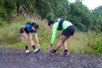 Asian Indonesian couple stretching before trail run, outdoor exercise and sustainable lifestyles