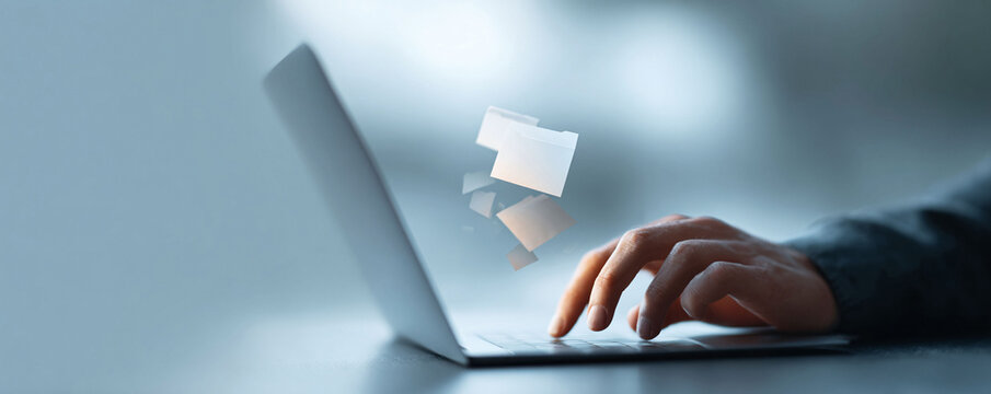 Closeup of hands typing on laptop with floating document icons, suggesting digital data management, cloud storage, information flow. Business, technology, efficiency concept.