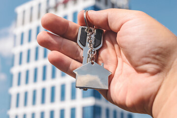 Hand Holding House Keys and Fob Modern Building Background, Home Ownership