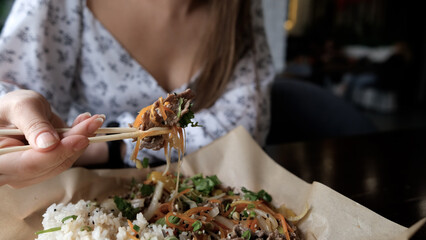 Close-up of Caucasian woman eating pan-Asian cuisine
