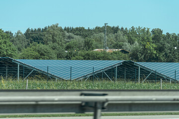 Solar panels generate clean energy near a highway in a green landscape on a sunny day