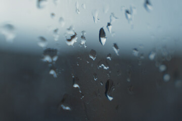 Raindrops on a foggy window create an abstract texture. The atmosphere of cloudy weather, nature, melancholy, comfort and tranquility