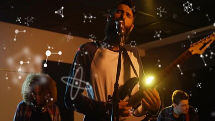 Drummer striking kit sparking molecular graphics in rock studio, frontman singing playing guitar