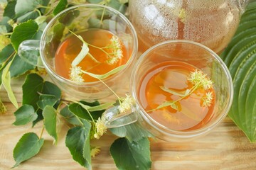 Linden tea in a glass cup with fresh linden flowers, on a wooden background. Medicinal herbal tea.