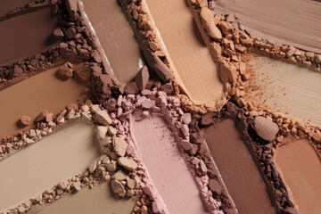 Crushed face powders and pressed makeup swatches in warm neutral and pink tones arranged in overlapping close-up composition