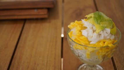 Close-up of a refreshing Indonesian shaved ice dessert topped with avocado, coconut, and jackfruit,...