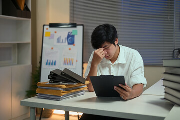 Young businessman feeling stressed while working late at night
