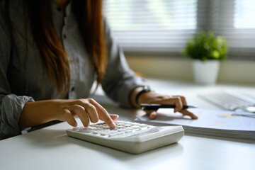 Businesswoman calculating expenses and analyzing reports in a modern office