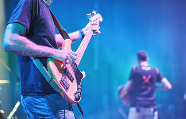 Close-up of bass guitarist playing on stage during live concert