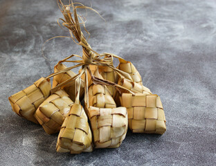 Close up view of Ketupat, an Indonesian traditional cuisine very popular during Hari Raya Idul Fitri served on a wooden table. This is made of the white rice, usually served with opor ayam on Ied day.