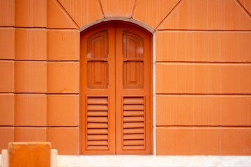 Fototapeta na wymiar Orange Arched Window on Textured Wall