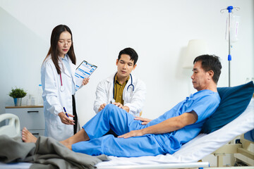 Doctor and nurse assess senior patient’s leg injury in hospital, using tablet x-ray to explain...