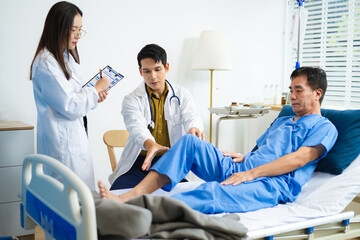 Doctor and nurse assess senior patient’s leg injury in hospital, using tablet x-ray to explain...
