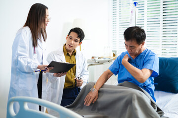 Obraz premium Doctor and nurse assess senior patient’s leg injury in hospital, using tablet x-ray to explain diagnosis and care.