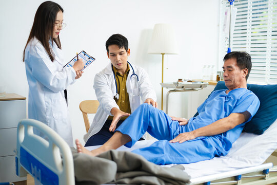 Doctor and nurse assess senior patient’s leg injury in hospital, using tablet x-ray to explain diagnosis and care.