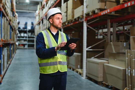 Portrait of warehouseman with clipboard checking delivery, stock in warehouse. Warehouse worker preparing products for shipment