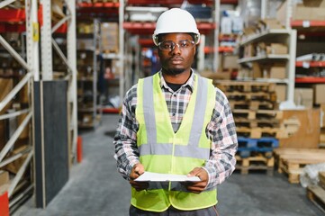 Portrait of african american warehouseman with clipboard checking delivery, stock in warehouse....