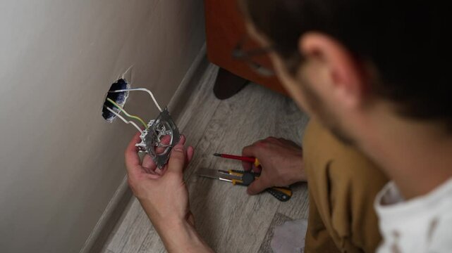 Professional electrician installing wall sockets with precise wiring techniques inside residential interior, showcasing skilled manual craftsmanship and technical expertise
