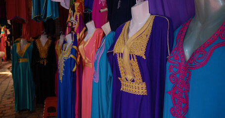 Stall selling colorful traditional clothing with fine embroidery in the old town of Sousse. Street market with clothes specific to Tunisia.