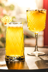 Two refreshing yellow cocktails on a sunlit table, served in elegant textured glasses.