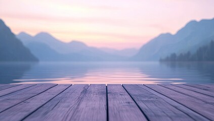 Wooden dock on a tranquil lake at sunrise. Soft pastel hues of pink and purple fill the sky, blending into a hazy mountain backdrop