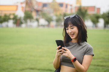 Happy solo Southeast Asian woman teenager blogger and world travel explorer uses smartphone map...