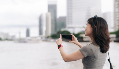 Solo southeast asian woman teenager blogger world travel explorer take photo with smartphone...