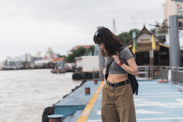 Solo southeast asian woman teenager blogger smartphone wait express boat friend Chao Phraya river Bangkok. World travel explorer tourism concept local cultural experience Thailand Asia