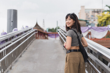 Smiling solo Southeast Asian woman teenager blogger on world travel enjoys local cultural experience. Tourism concept for an explorer in Bangkok Thailand in Asia
