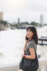 Happy solo southeast asian woman teenager blogger and explorer express joy on world travel tourism. local cultural experience using smartphone near Chao Phraya River in Bangkok Asia Thailand