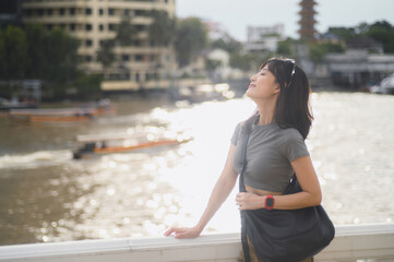 Solo young southeast asian woman teenager blogger on world travel tourism. Local cultural experience for explorer with smartphone by Chao Phraya River Bangkok. Asia tourism concept in Thailand