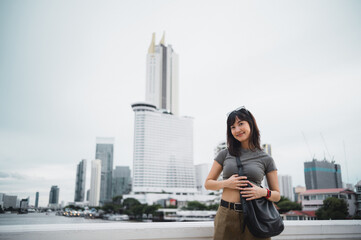 Happy solo young southeast asian woman teenager blogger explorer enjoying world travel. Local cultural tourism experience concept with smartphone in Bangkok Thailand Asia by Chao Phraya River