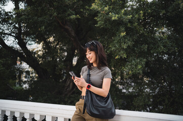 Young southeast asian woman teenager blogger searching map guide on smartphone. World travel explorer on local cultural experience in Bangkok Thailand. Asia tourism concept near Chao Phraya River