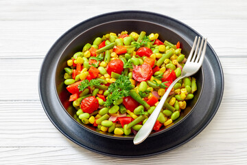 succotash of corn, beans, tomatoes, in black bowl