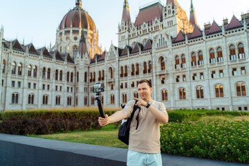 Obraz premium Travel blogger filming with smartphone in front of Hungarian Parliament in Budapest