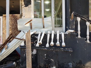 Storefront in a city shows extensive damage after a crash or tornado. Debris is scattered across...