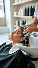 Young woman enjoying relaxing hair wash at beauty salon with eyes closed, receiving professional haircare treatment.