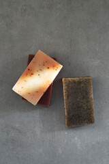 Natural soap bars in earthy tones on a minimalist concrete gray background with dramatic deep light