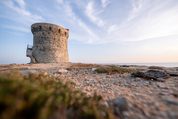 Średniowieczna wieża strażnicza na skalistym wybrzeżu o zachodzie słońca   © RTEKA